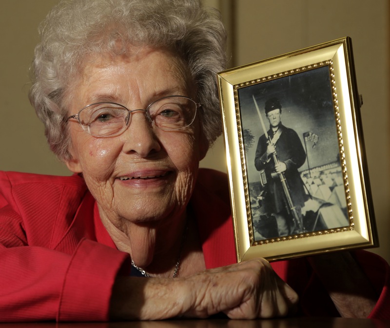 Juanita Tudor Lowrey, age 86, poses with a photo of her father, Civil War veteran Hugh Tudor Tuesday, March 19, 2013, in Kearney, Mo. Lowrey received pension benefits related to her father's Civil War service until she was 18 after her father died when she was 2 years old. (AP Photo/Charlie Riedel)