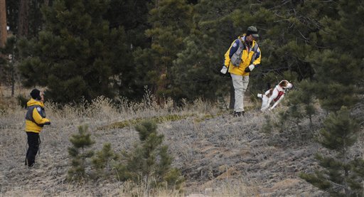 Searchers use a dog Wednesday to search the area around the Monument, Colo., home of Colorado Department of Corrections Executive Director Tom Clements, who was shot and killed Tuesday evening.