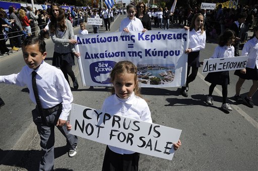 Students hold placards during a parade for Greek independence day celebrations at the southern port city of Limassol, Cyprus on Monday. Cyprus secured what its politicians described as a "painful" solution to avert imminent bankruptcy, agreeing early Monday to slash its oversize banking sector and make large account holders take losses to help pay to secure a last-minute euro10 billion (US$13 billion) bailout.