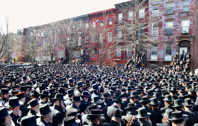 In this March 3, 2013, photo provided by VosIzNeias.com, Orthodox Jewish mourners gather outside the Congregation Yetev Lev D'Satmar synagogue in Brooklyn's Williamsburg neighborhood for the funeral of two expectant parents who were killed in a car accident early Sunday, in New York. The baby of Nachman and Raizy Glauber, a boy, was delivered prematurely by cesarean section and survived until the next morning, but died around 5:30 a.m. on Monday, March 4. Police were searching for the driver of a BMW and a passenger who fled on foot after slamming into the livery cab that was transporting the 21-year-old couple to a hospital. (AP Photo/VosIzNeias.com, Eli Wohl)