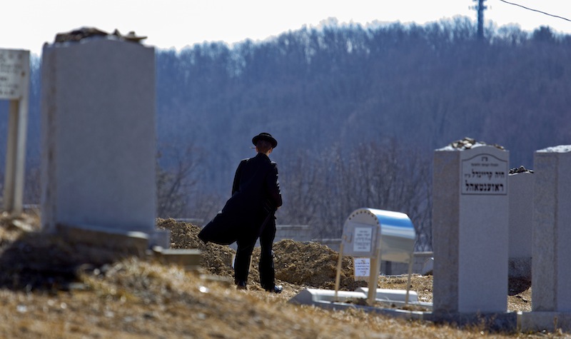 A person walks towards the graves of Nathan and Raizy Glauber, at the Satmar Cemetery 2 in Kiryas Joel, New York, Monday, March 4, 2013. The baby boy delivered prematurely after his parents, Nathan and Raizy Glauber, were killed Sunday in a New York City hit-and-run accident died Monday, March 4, 2013, a community spokesman said, while the search for the driver who fled on foot narrowed. (AP Photo/Craig Ruttle)