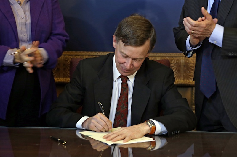Colorado Gov. John Hickenlooper is applauded by lawmakers as he signs the state's gun control bill into law at the Capitol in Denver on Wednesday, March 20, 2013. (AP Photo/Ed Andrieski, Pool)