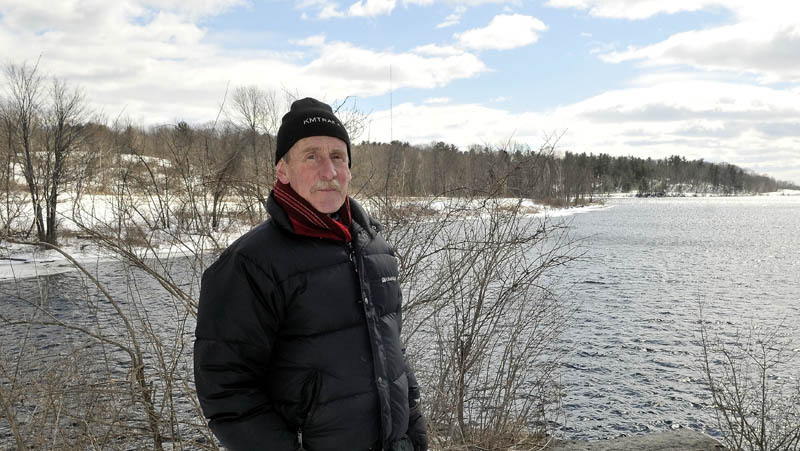 Peter Garrett, president of the Kennebec-Messalonskee Trails, stands on the bridge abutment at the southern end of the Rotary Centennial trail in Winslow on Saturday. Land recently donated for trail use by Madison Paper Industries appears in the background, along the shore of the Kennebec River on the Winslow side.