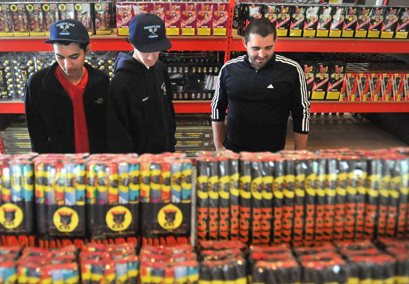 FIRED UP: Osman Castro, 18, left, Connor Shaw, 17, center, and Sam Picard, all from Presque Isle, browse the vast selection of fireworks at Pyro City Maine on China Road in Winslow Friday.