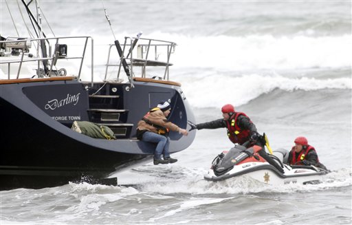 Rescuers attempt to grab a woman off the back of the 82-foot-long sailboat, the Darling, stuck in the surf off Pacifica, Calif., on Monday.