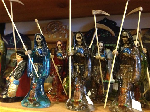 Statues of La Santa Muerte are shown at the Masks y Mas art store in Albuquerque, N.M., recently. In addition to showing up at drug crime scenes, the once-underground icon has been spotted on passion candles in Richmond, Va. grocery stores. The folk saint's image can be seen inside New York City apartments, in Minneapolis religious shops and during art shows in Tucson, Ariz.