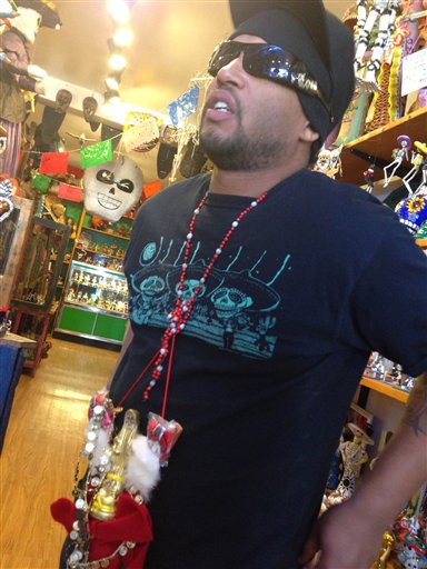 In this Feb. 13, 2013, photo, actor Gregory Beasley Jr., 35, wears a La Santa Muerte statue around his neck at the Masks y Mas art store in Albuquerque, N.M.