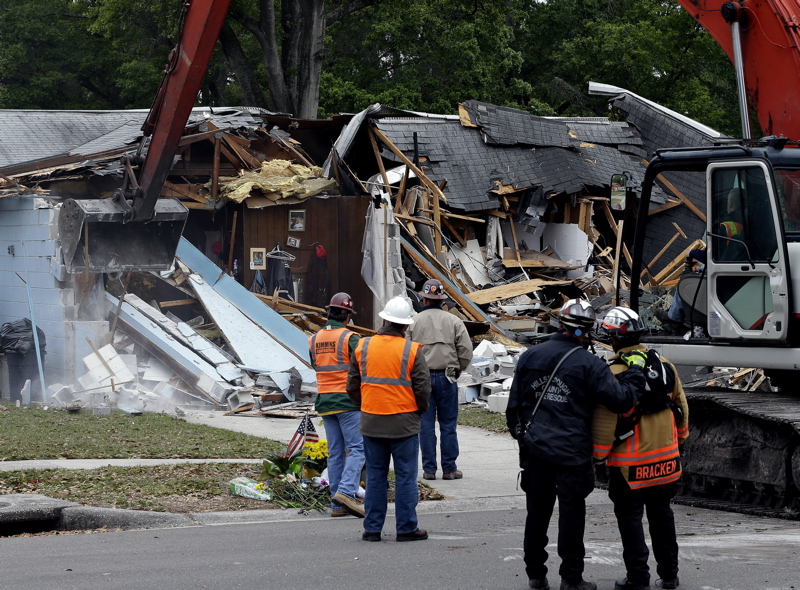 Demolition experts watch as the home of Jeff Bush, 37, is destroyed Sunday after a sinkhole opened up underneath it late Thursday evening swallowing Bush, 37, in Seffner, Fla.