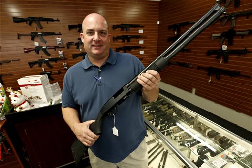 Former Tucson, Ariz. mayoral candidate Shaun McClusky poses with a shotgun at Black Weapons Armory in Tucson on Thursday. The weapon is similar to those to be given away as part of a privately funded program he is launching to provide residents in crime-prone areas with free shotguns so they can defend themselves against criminals.