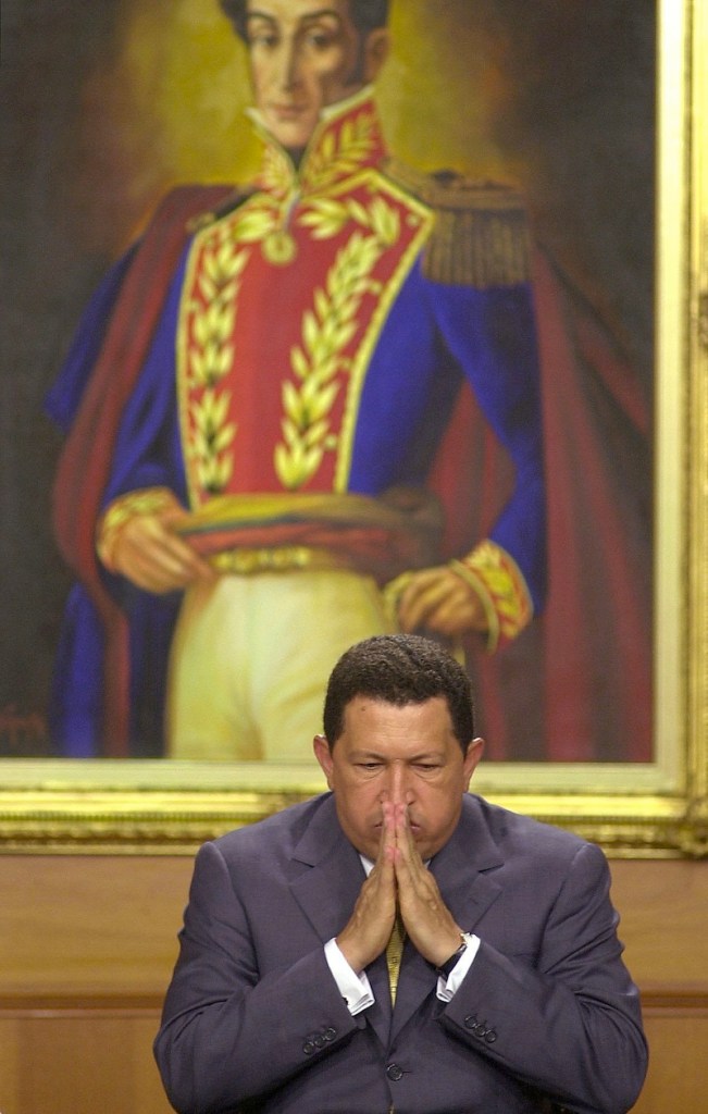 In this Dec. 5, 2001 file photo, Venezuela's President Hugo Chavez gestures before a painting of Venezuelan independence hero Simon Bolivar at an event at Miraflores presidential palace in Caracas, Venezuela. Venezuela's Vice President Nicolas Maduro announced on Tuesday, March 5, 2013 that Chavez has died. Chavez, 58, was first diagnosed with cancer in June 2011. (AP Photo/Leslie Mazoch, File)