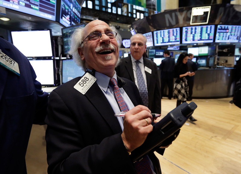 Trader Peter Tuchman smiles as he works on the floor of the New York Stock Exchange on Tuesday. The Dow reached a new high Tuesday.