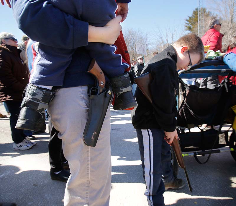 Suzanne Hiltz of Chelsea holds her son, Samson, 2, with a Ruger Single-Six .22 caliber revolver on her hip, while attending a rally in Wiscasset on Saturday protesting gun control legislation and supporting gun rights. At right is Hiltz's son Jonah, 7, holding a .22-caliber youth model rifle.