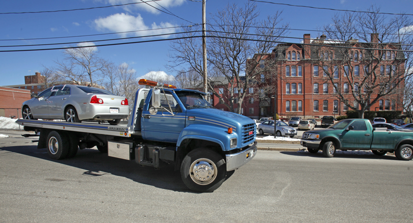 A flatbed tow truck pulls away Tuesday morning from Parish Place Apartments in Biddeford with a silver Chevy Malibu with Massachusetts plates. Residents say it was the car in which a man's body was found this morning.