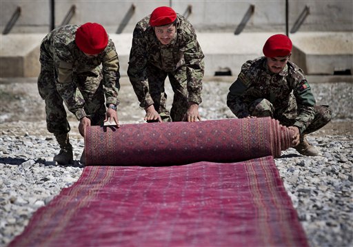 Afghan National Army soldiers roll up the red carpet after the hand over ceremony of the Parwan Detention Facility from U.S. military control to Afghan authorities in Bagram, outside Kabul, Afghanistan, Monday, March 25, 2013. The handover of Parwan Detention Facility ends a bitter chapter in American relations with Afghanistan's mercurial president, Hamid Karzai, who demanded control of the prison as a matter of national sovereignty. (AP Photo/Anja Niedringhaus)