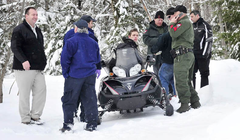 Seventeen-year-old Nicholas Joy is surrounded by game wardens and others who brought him out of the woods Tuesday. At right is Joseph Paul who picked up Joy on the snowmobile and at left is Carrabassett Valley police chief Mark Lopez.