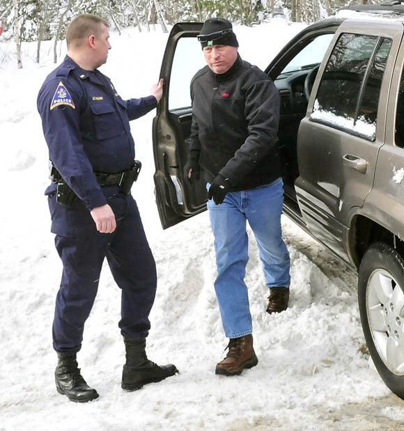 Bob Joy, father of missing skier Nicholas Joy, arrives at the site where his son was brought out by snowmobile Tuesday morning. At left is Carrabassett Valley police officer Randy Walker.