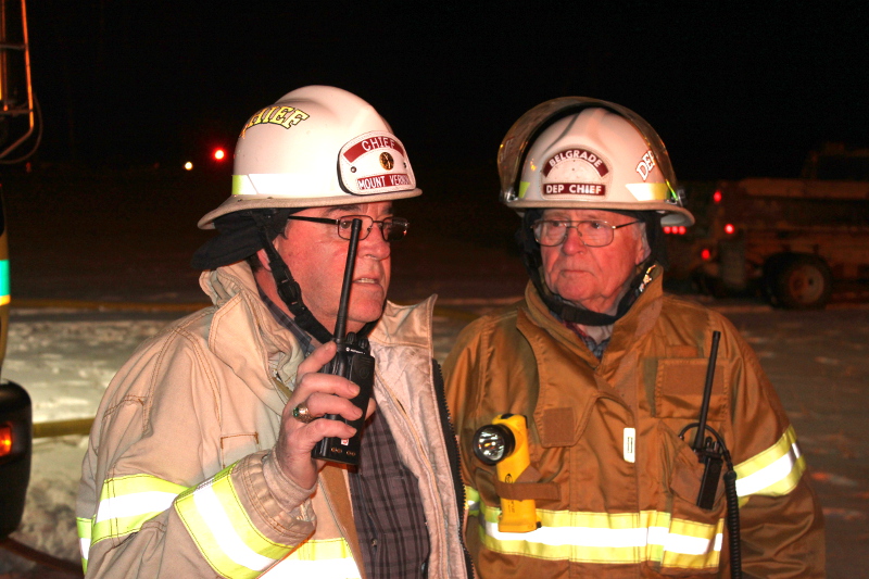 Mount Vernon Fire Chief Dana Dunn, left, and Belgrade Deputy Fire Chief Bill Pulsifer discuss tactics while fighting a fire on Bean Road in Mount Vernon on Sunday.