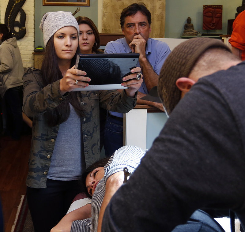 Kristian Spataro of Toronto takes a photo with a tablet device of her aunt, Sharon Boucher of Acton, Mass., getting a tattoo in honor of the late Robyn Hesseltine at Tsunami Tattoo in Portland on Thursday, Feb. 28, 2013.