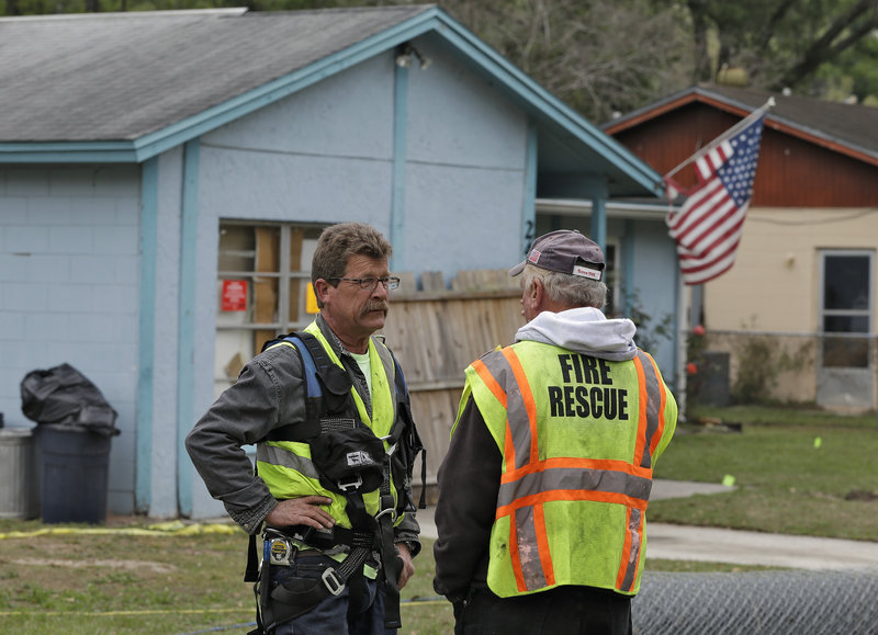 Engineers discuss their findings while investigating a sinkhole that opened up beneath a home in Seffner, Fla., on Thursday.
