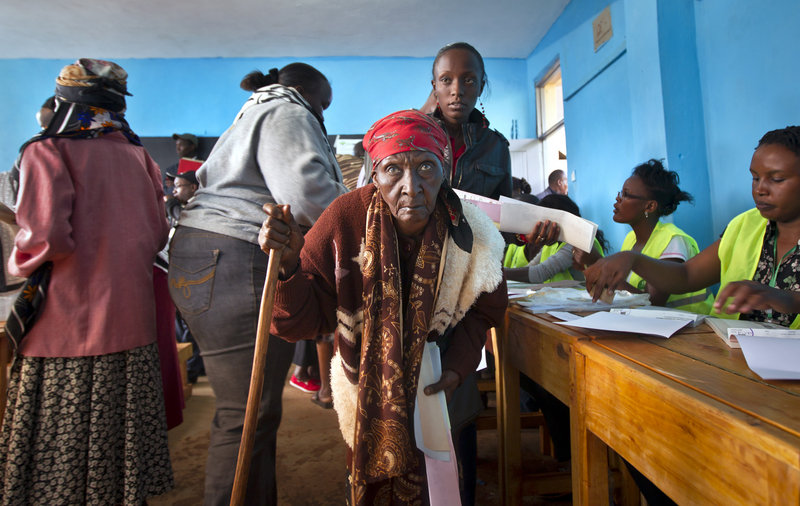 A woman walks with a cane to cast her vote at a primary school near Gatundu, north of Nairobi, in Kenya on Monday.