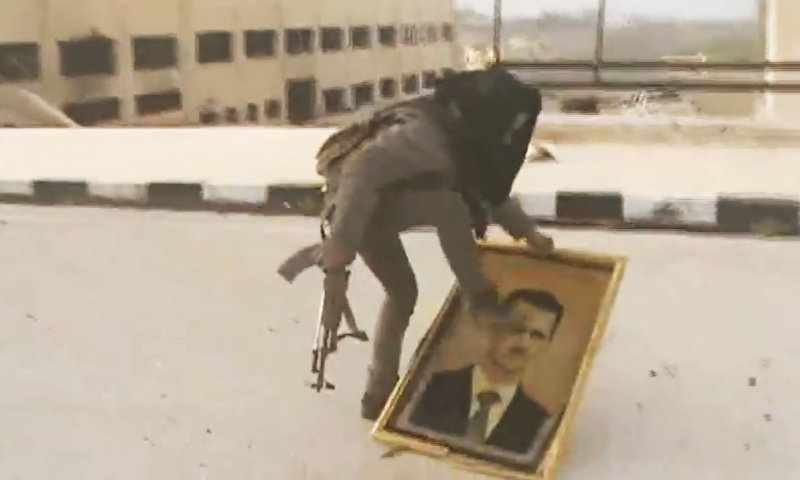 A Syrian rebel fighter stomps on a picture of Syrian President Bashar Assad after rebels seized the police academy complex in Khan al-Asal, in the province of Aleppo, Syria, on Sunday.