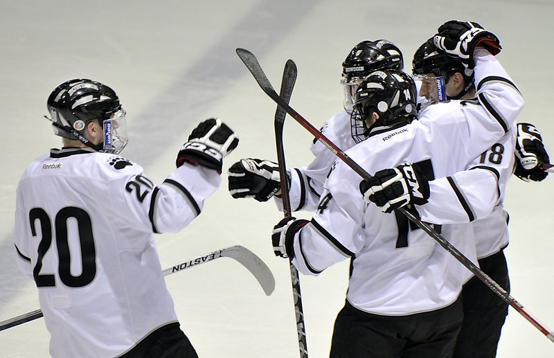 John McGinnis, left, celebrates Bowdoin’s first goal Wednesday scored by Jay Livermore, 18, in the first period at Brunswick. Bowdoin won, 5-2.