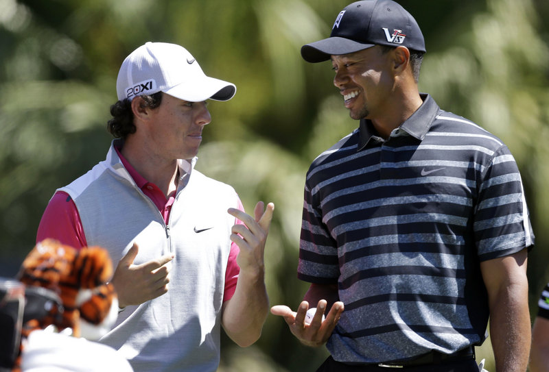 Rory McIlroy, left, shares a moment with Tiger Woods during Thursday’s outing in Doral, Fla., but his 73 left him with little to smile about as he’s still finding last year’s success a tough act to follow.