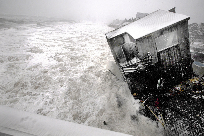 A house on the Plum Island seacoast in Newbury, Mass., sits partially collapsed into the churning surf, driven by winds from a slow-moving ocean storm at high tide Friday. The storm dropped up to a foot of snow on some parts of New England.