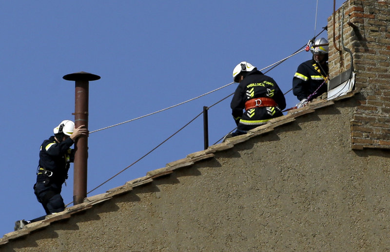 Firefighters place the chimney on the roof of the Sistine Chapel on Saturday at the Vatican, where cardinals will gather to elect the new pope. Smoke from the burning ballot papers will tell the world when a decision has been reached on a successor to Benedict XVI.