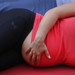 A pregnant woman touches her stomach as people practice yoga on the morning of the summer solstice in New York's Times Square