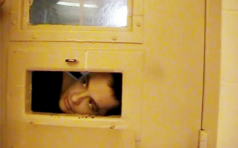 Paul Schlosser peers out the food tray slot in his cell door June 10, 2012. Schlosser, who had injured himself, took the dressing off his wound and was put under observation and videotaped through this food tray slot.