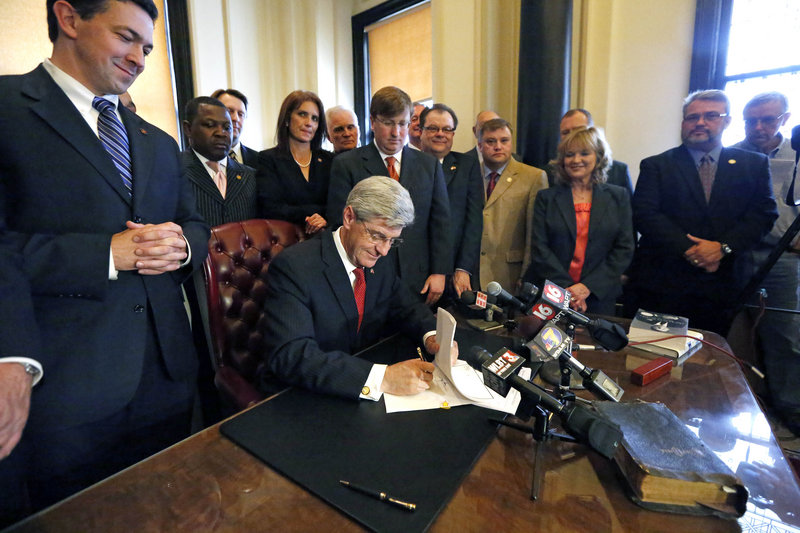 Lawmakers and others watch Gov. Phil Bryant sign the Mississippi Student Religious Liberties Act allowing students to express religious sentiments without fear of reprisals.