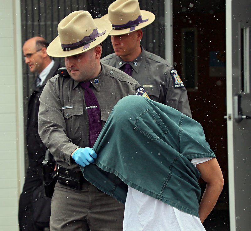 New York State Police lead David Renz out of a state police barracks on Friday.