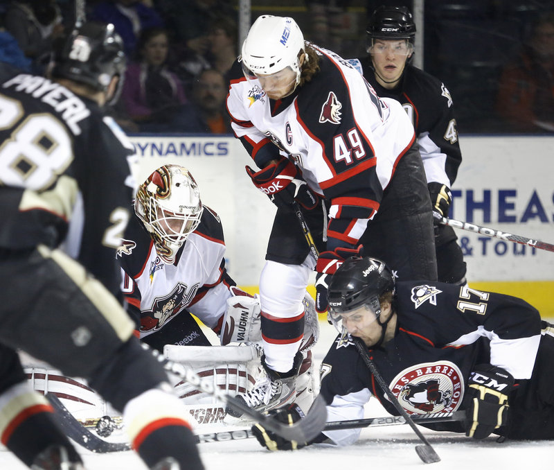 Portland goaltender Chad Johnson makes a save during first-period action of Saturday’s game while teammate Alexandre Bolduc gives a stick-shave to a prone Paul Thompson.