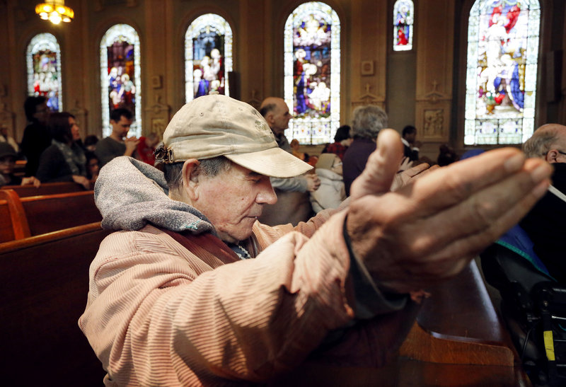 Antonio Hernandez of Portland lifts his hands in prayer Sunday during Mass at Sacred Heart/St. Dominic church in Portland.