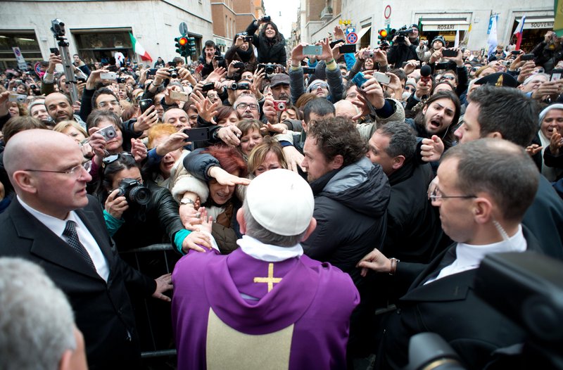 Pope Francis greets onlookers in Rome on Sunday. The pope began his first Sunday as pontiff by making an impromptu appearance to the public from a side gate of the Vatican.