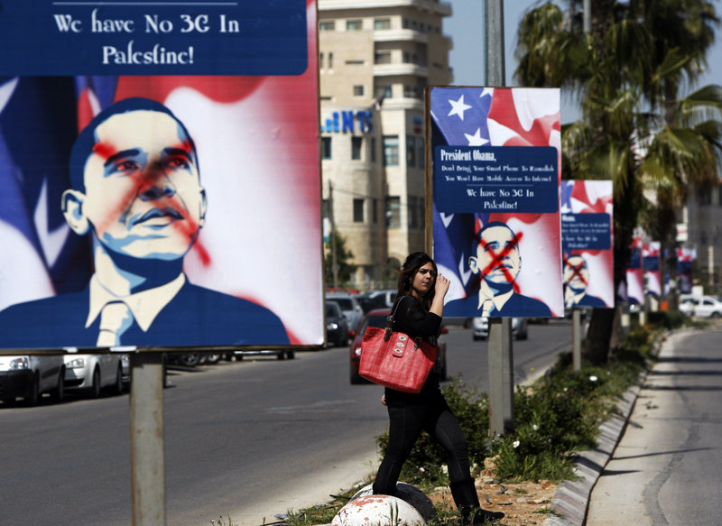A Palestinian woman in the West Bank city of Ramallah walks past vandalized posters of Barack Obama in the days before the U.S. president’s planned visit to the Middle East aimed at restarting Israeli-Palestinian negotiations.