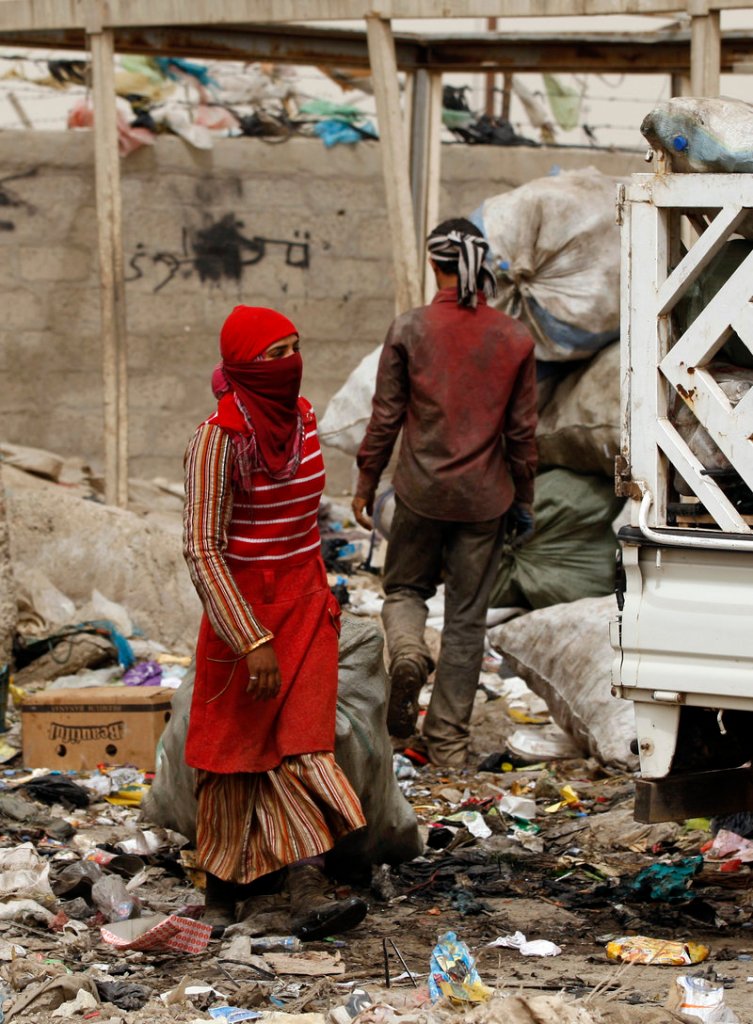 An Iraqi woman carries a bag of recyclable materials at a garbage dump in the Shiite enclave of Sadr City in Baghdad, Iraq, on Sunday. According to the manager of the dump, the people who salvage plastic and aluminum make an average of $8 per day re-selling the materials. The intractable nature of Baghdad politics has widened the country’s ethnic and sectarian fault lines.