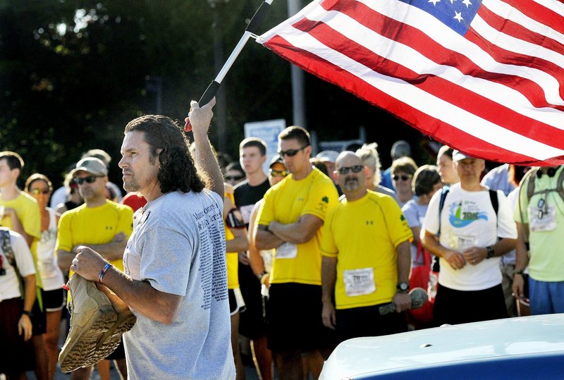 In this Aug. 19, 2012 file photo, Carlos Arredondo of Boston waves a flag and holds the boots of his fallen son, Lance Cpl. Alexander Arredondo, 20, at the start of the Run for the Fallen in Ogunquit. Alexander died while serving in the Marine Corps in Iraq in 2004.