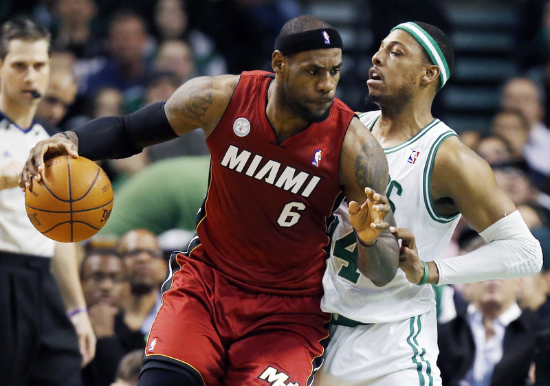 Miami’s LeBron James puts his shoulder into Boston’s Paul Pierce during the Heat’s 105-103 win at Boston on Monday. Boston’s Kevin Garnett sat out the game with the flu.