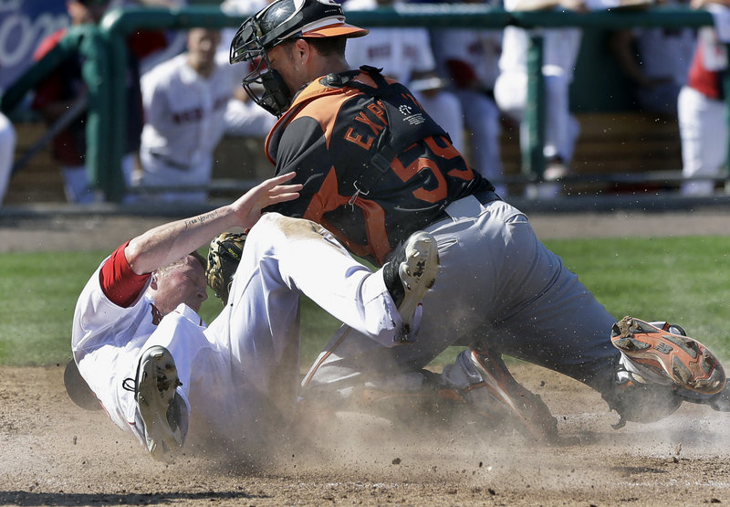 Jeremy Hazelbaker of the Boston Red Sox slides safely into the plate Tuesday, beating a tag applied by catcher Luis Exposito of the Baltimore Orioles. Both are former Sea Dogs players, though not in the same season. Baltimore won the spring-training game, 8-7.