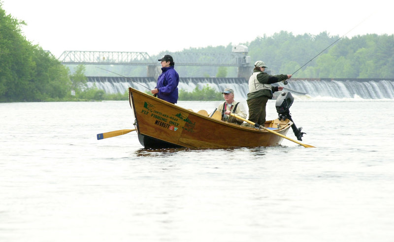 In this 2002 file photo, fishing guide Jim Thibodeau rows a couple of fly fishing clients on the Kennebec River below Shawmut Dam. Maine-based environmental organizations are seeking a federal court order to shut down turbines at four hydroelectric dams on the Androscoggin and Kennebec rivers this spring in order to protect this year's Atlantic salmon run.