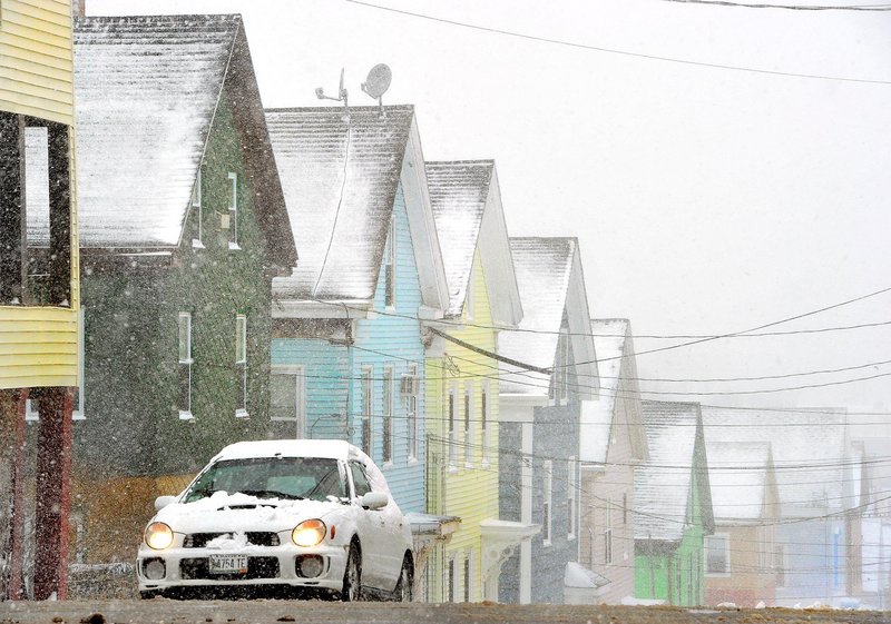 A car climbs the hill and turns onto Cumberland Avenue in Portland as the snow begins to fall on Tuesday, March 19, 2013. In the background, pastel colored houses on Smith Street.
