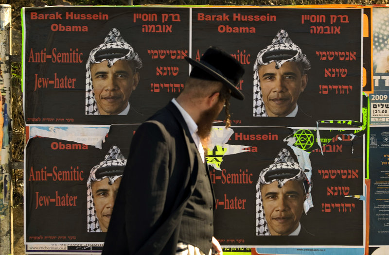 An Ultra Orthodox Jewish man walks past posters depicting President Barack Obama wearing Arab headdress, in Jerusalem, in this 2009 file photo. Obama’s assurances of the U.S. commitment to Israel’s security remains a tough sell.