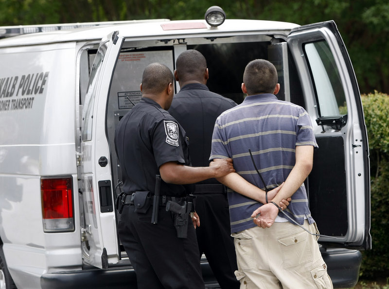 A suspect is loaded into a DeKalb police prisoner transport van during a “pill mill” raid at Southern Health Management next to police headquarters near Tucker, Ga., in 2012.