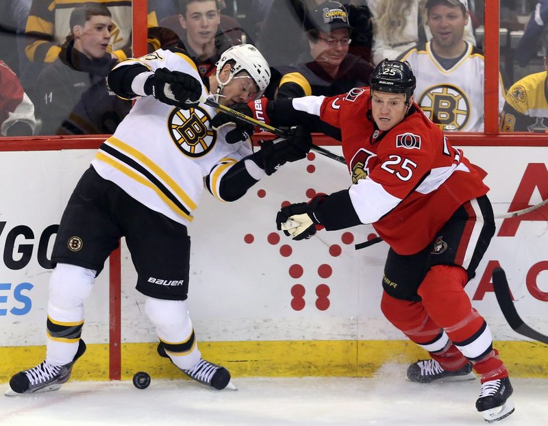 Boston’s Aran Johnson and Ottawa’s Chris Neil joust along the boards during Thursday night’s game in Ottawa, won by the Bruins on a goal in the third period.