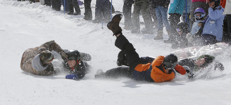 The team known as The Bed Bugs, Tim Hiltz, left, and his sons Brayden, Logan and Dillon, left to right, hit the snow after falling off their mattress while competing at Shawnee Peak in Bridgton on Saturday. The team came in fifth place.