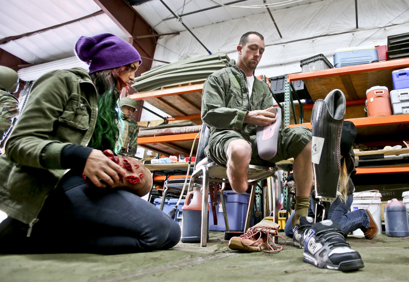Former Navy corpsman Joel Booth, who lost a leg in Afghanistan, prepares with the help of a makeup artist to play his role as a downed helicopter pilot in a military training exercise at San Diego-based Strategic Operations.