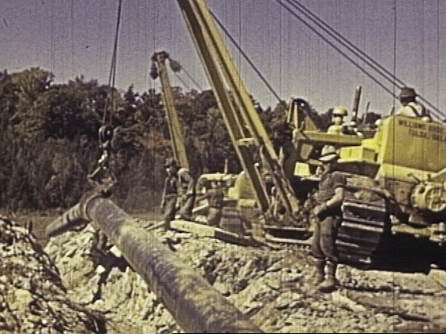 Workers in 1941 use cranes called boom cats to lower sections of the Portland-Montreal pipeline into the ground in Vermont. Crews moved at “emergency speed” to meet wartime oil transportation needs.