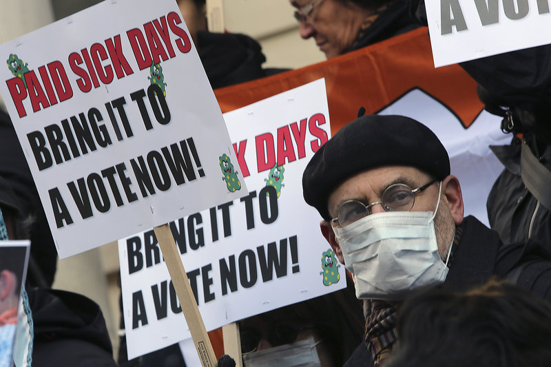 Activists hold signs during a rally at New York’s City Hall on Jan. 18 to call for action on a proposal to require employers in New York City to provide paid sick leave. A proposal before Congress would require employers nationwide to allow up to seven paid sick days a year.